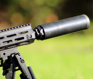 Close-up view of suppressor attached to the end of an automatic rifle with LMT Advanced Technologies LLC stamped into the suppressor.